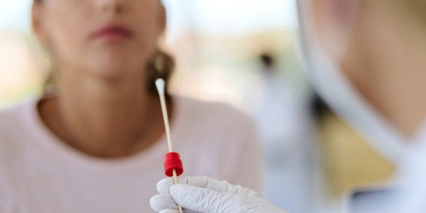 Women receiving a nasal swab COVID-19 test from a medical professional