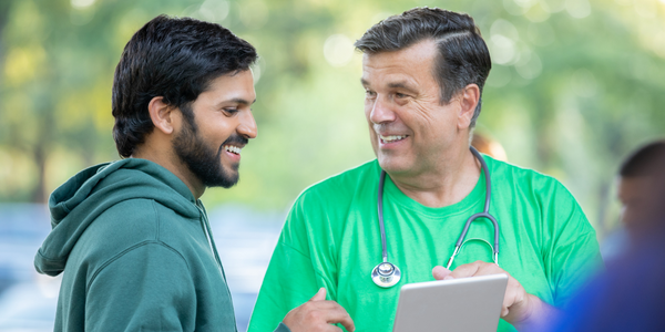 A nurse looking at a tablet checking in a employee at a health fair