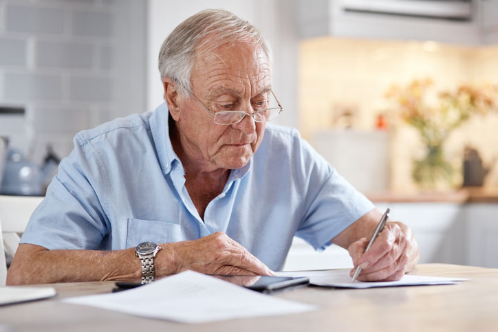 Elderly man filling out a paper health assessment in his home